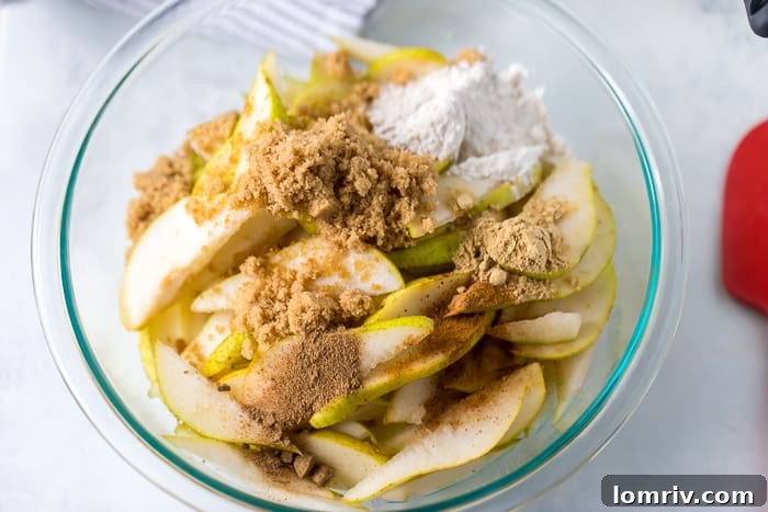 A serving of pear crisp, revealing the tender spiced pear filling beneath the crunchy oat topping.