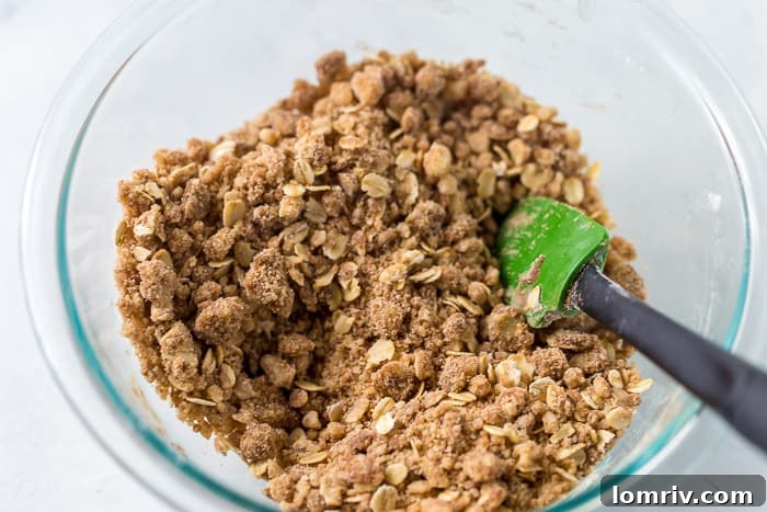 A close-up of the crispy oat topping, featuring visible oats and chunks of browned butter for texture.