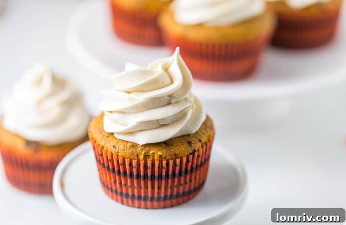 Close-up of a Pumpkin Spice Latte Cupcake, showcasing the sweet coffee cream cheese frosting and a sprinkle of spice.