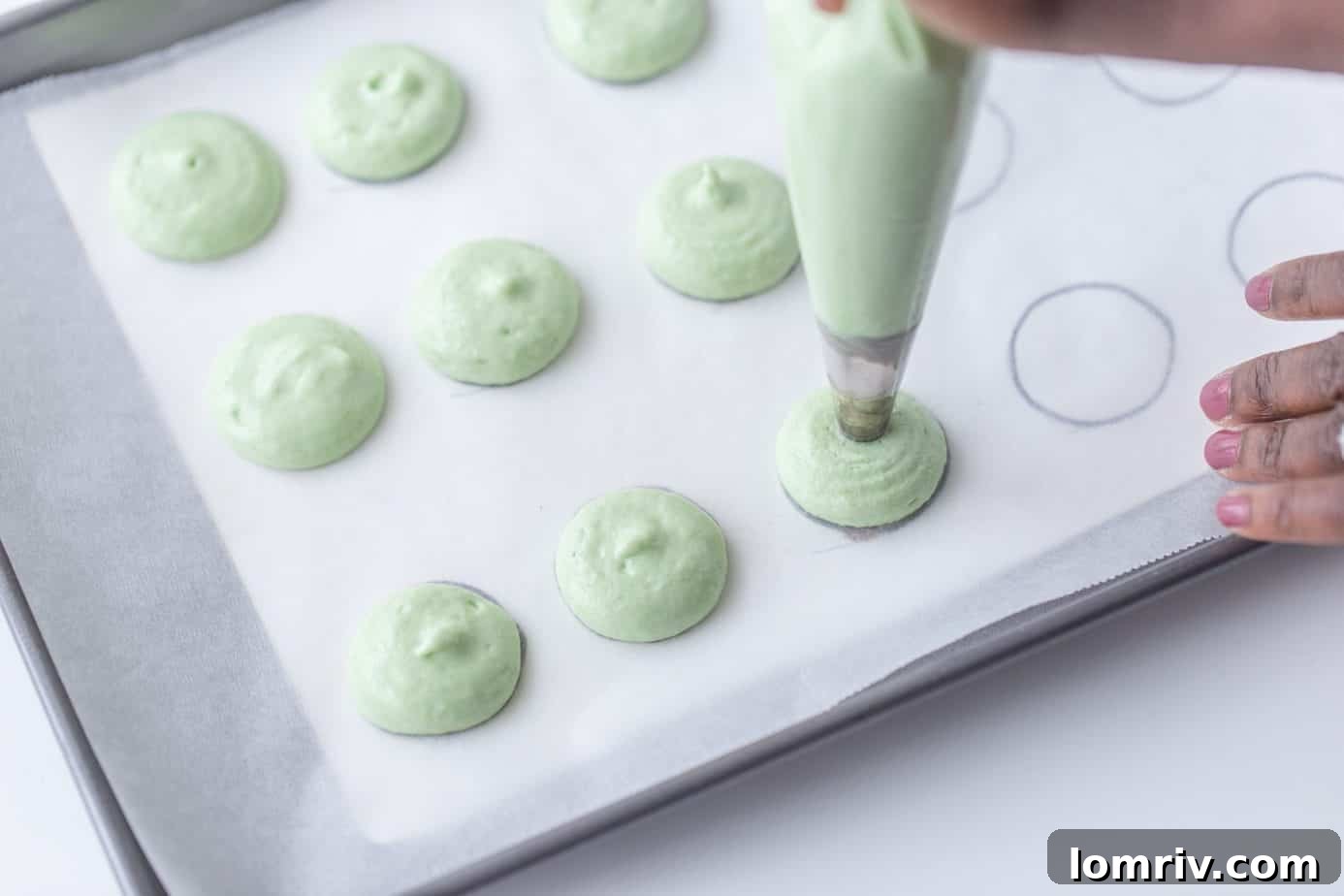 Piping macaron batter for lemon lime macarons onto a baking sheet