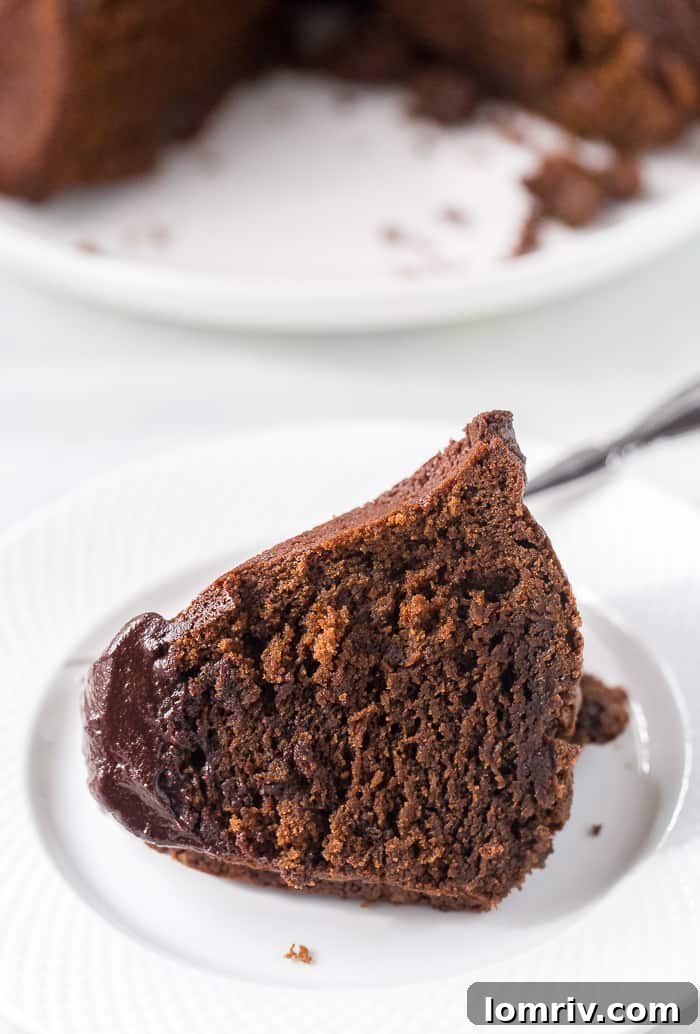 Close-up of a generously iced Chocolate Bundt Cake, ready to be served.