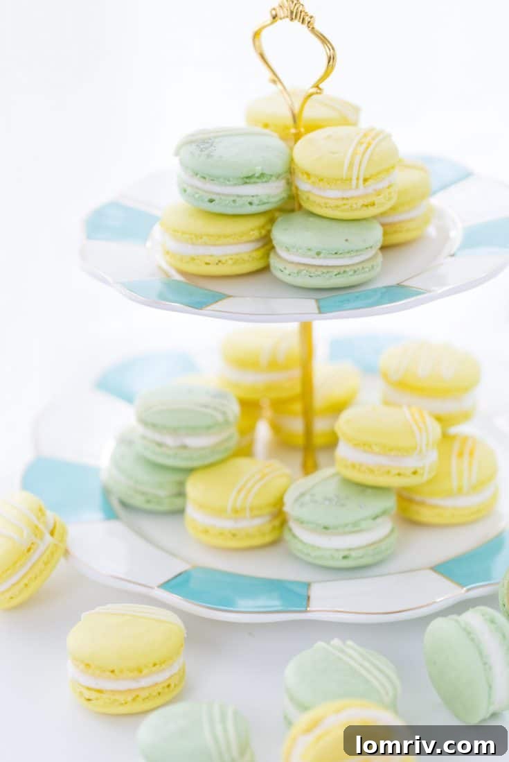 A close-up of macaron batter being folded with a rubber spatula in a glass bowl, demonstrating the macaronage technique.