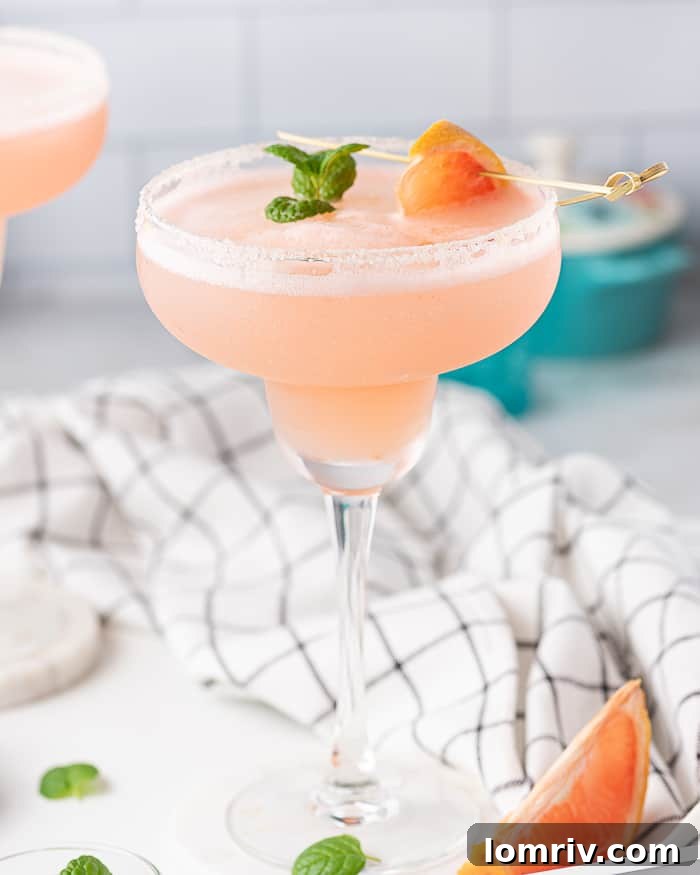 A perfectly blended Frozen Grapefruit Margarita in a salt-rimmed glass, garnished with a fresh grapefruit slice.