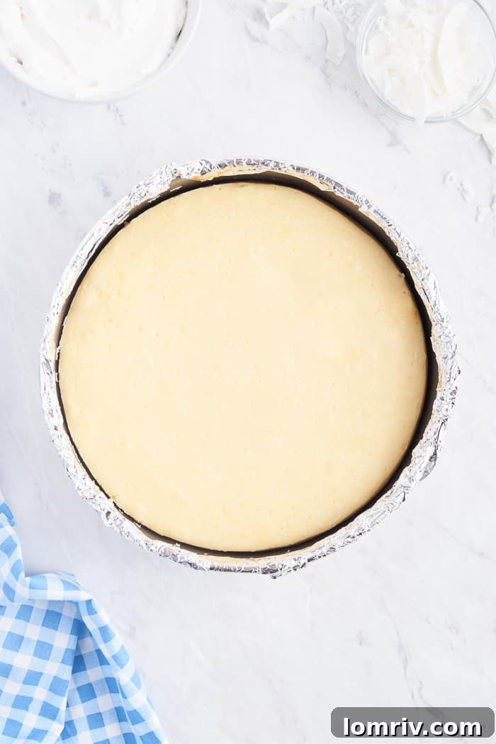 A perfectly baked Coconut Cheesecake with set edges and a slightly jiggly center, just out of the oven after its water bath.