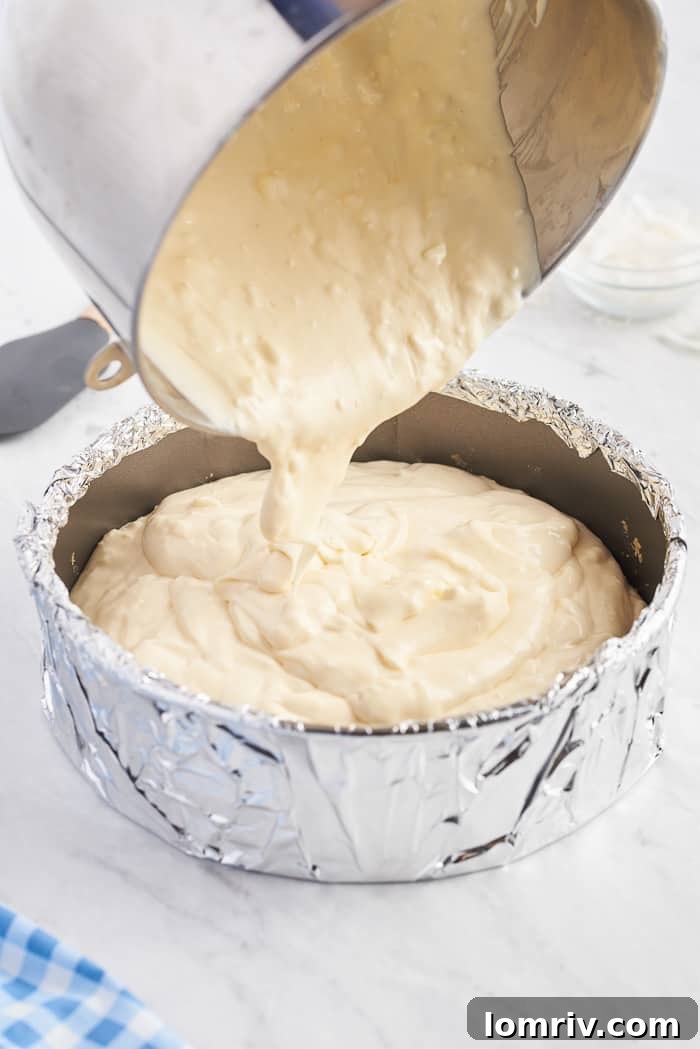 Smooth coconut cheesecake batter poured into the cooled graham cracker crust in a springform pan.