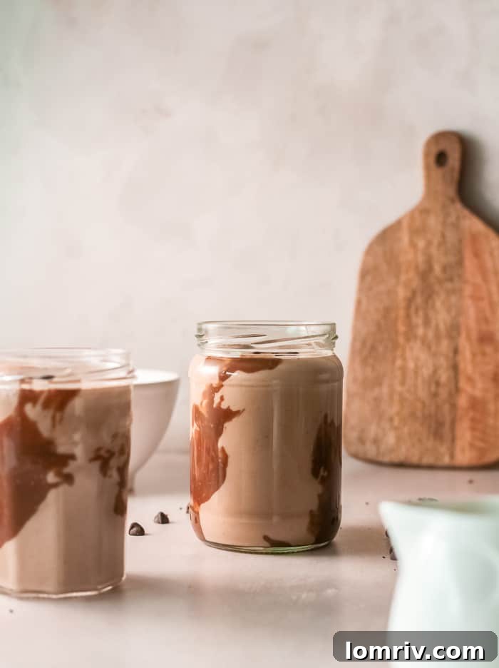 Hand holding a glass of Banana Bread Smoothie against a blurred background
