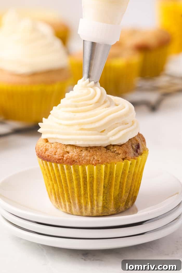 Finished Hummingbird Cupcakes with cream cheese frosting and a pecan garnish.