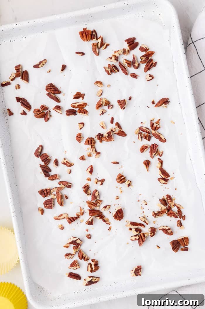 Pecans spread on a baking sheet, ready for toasting for Hummingbird Cupcakes.