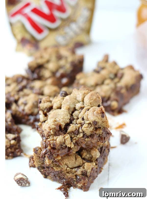A close-up of a single Salted Caramel Twix Cookie Bar, showing the layers of cookie, caramel, and Twix