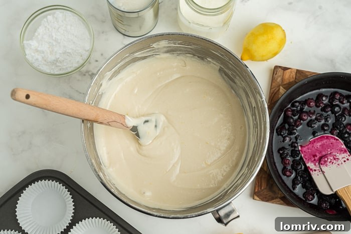 Filling cupcake liners with batter for Coconut Blueberry Cupcakes, showing the first layer.