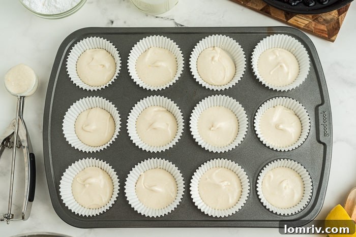 Adding a spoonful of blueberry compote on top of the first layer of cupcake batter.