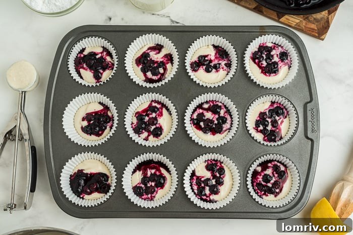 Covering the blueberry compote with more cupcake batter to fill the tin two-thirds full.