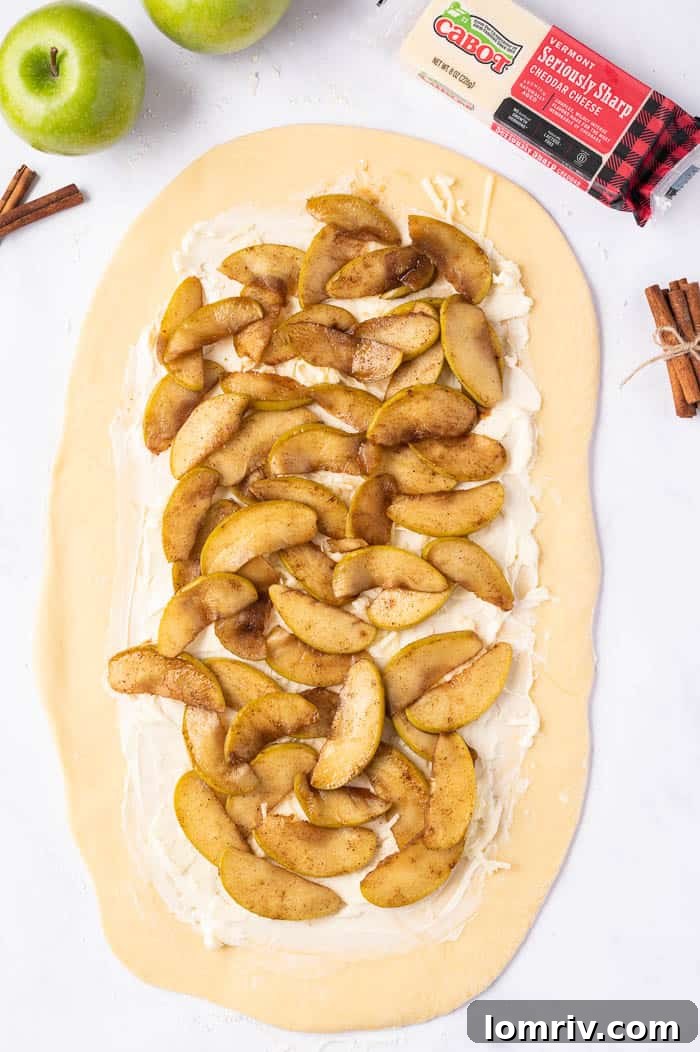Apple pie filling and shredded cheddar cheese layered onto buttered dough