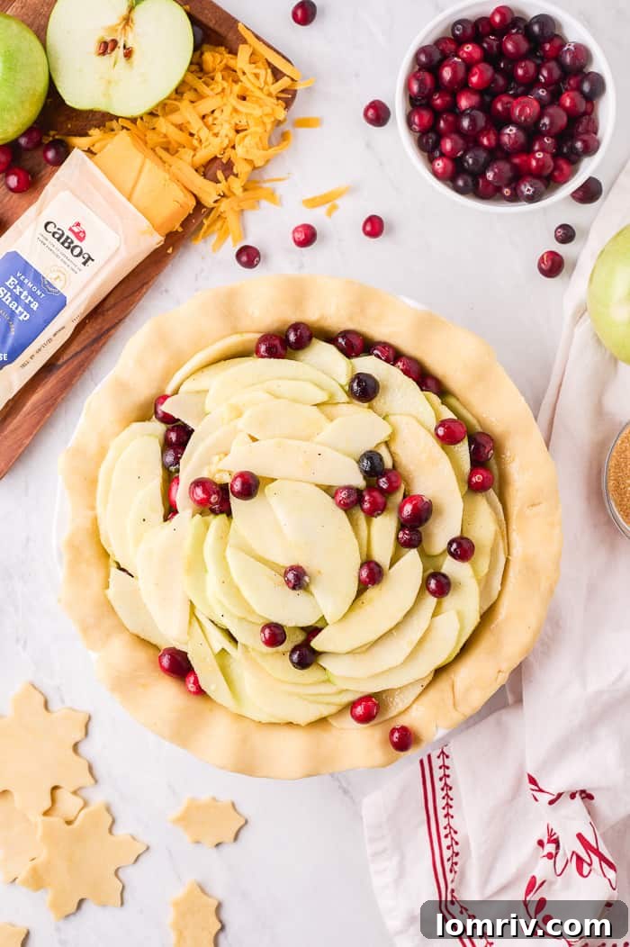 Hands carefully spooning the apple cranberry filling into the pie crust