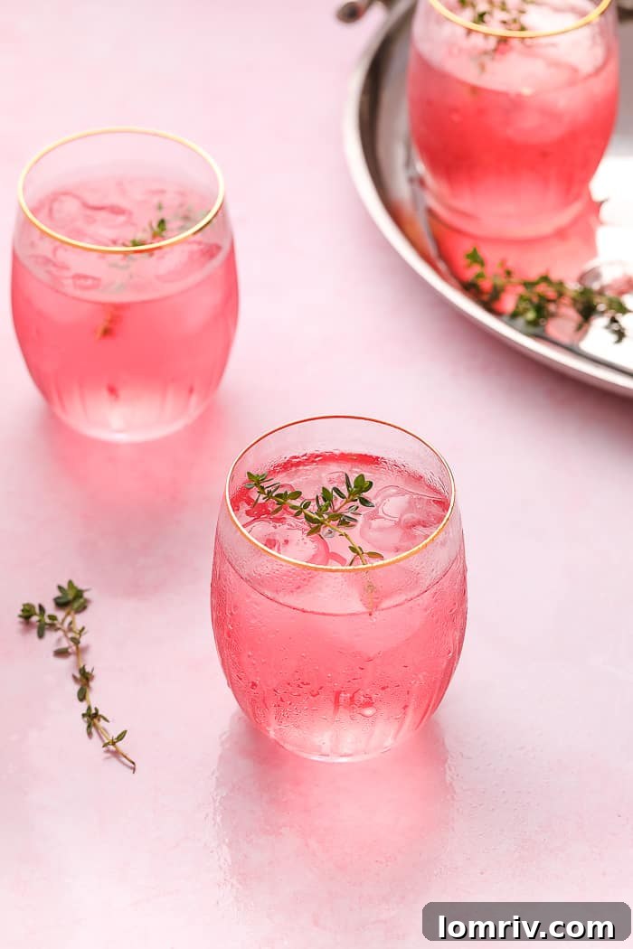 Several Pink Lemonade Cocktails with thyme and edible flowers