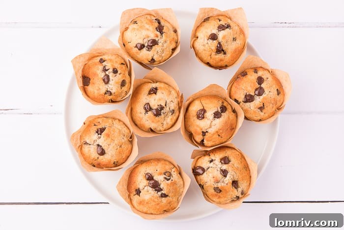 Close-up of a stack of fluffy Banana Chocolate Chip Muffins, highlighting their golden tops and visible chocolate chips