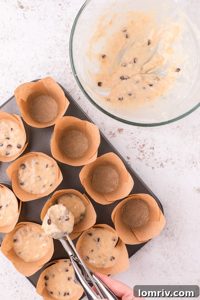 Banana Chocolate Chip Muffin batter scooped into a muffin tin with liners