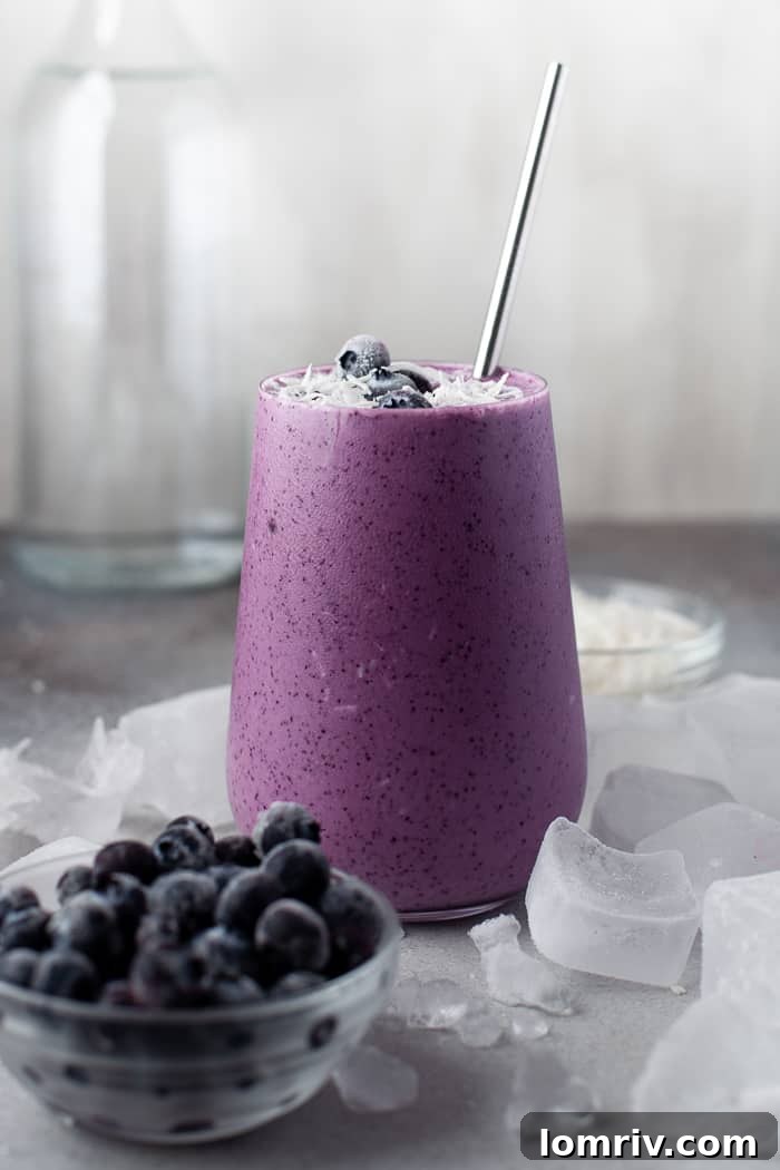 Healthy Blueberry Coconut Smoothie with fresh blueberries and coconut flakes scattered around.