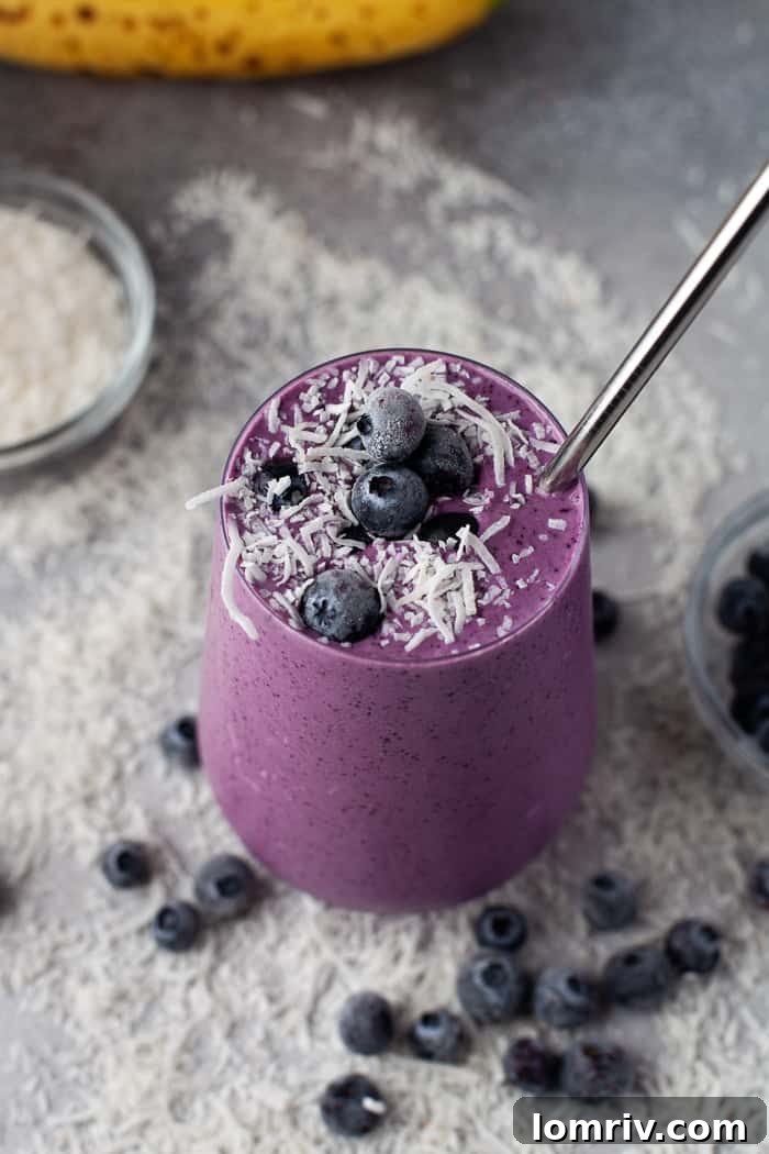 Healthy Blueberry Smoothie in a tall glass, garnished with blueberries and coconut flakes.