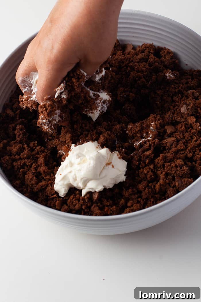Crumble chocolate cake mixed with cream cheese, ready to be shaped into cake pops.