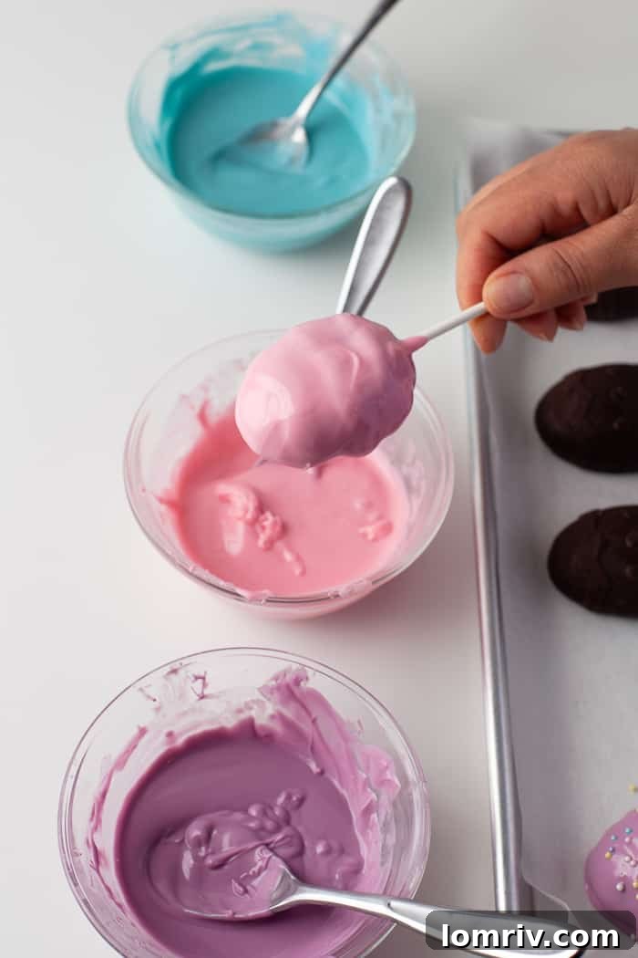 An Easter Cake Pop being dipped into melted candy coating, with a lollipop stick inserted.