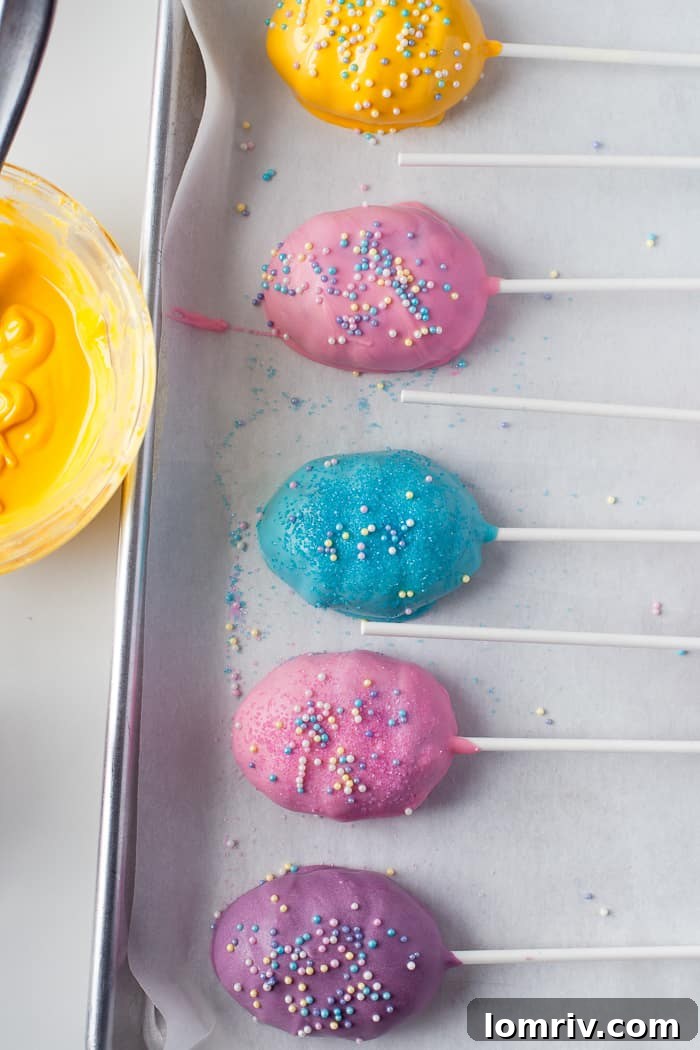 Decorated Easter Cake Pops covered in various sprinkles, resting on parchment paper.