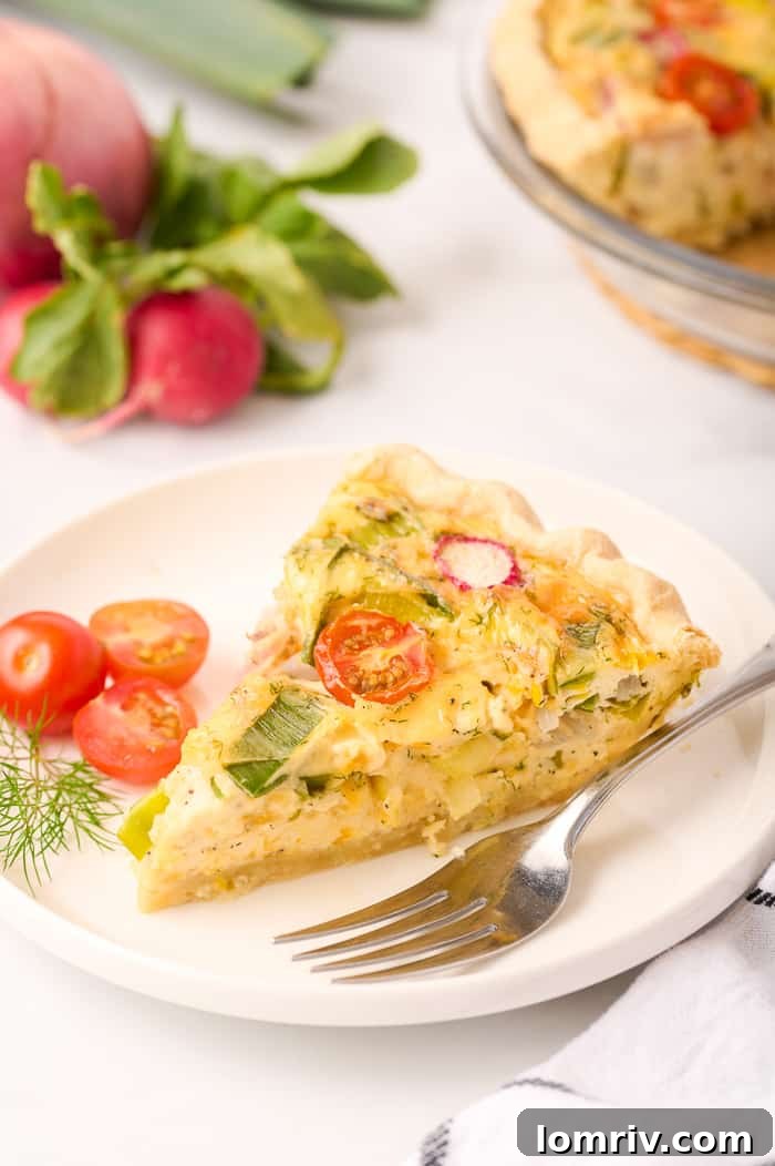 Beautifully plated slice of Farm Vegetable Quiche, showing flaky crust and colorful filling