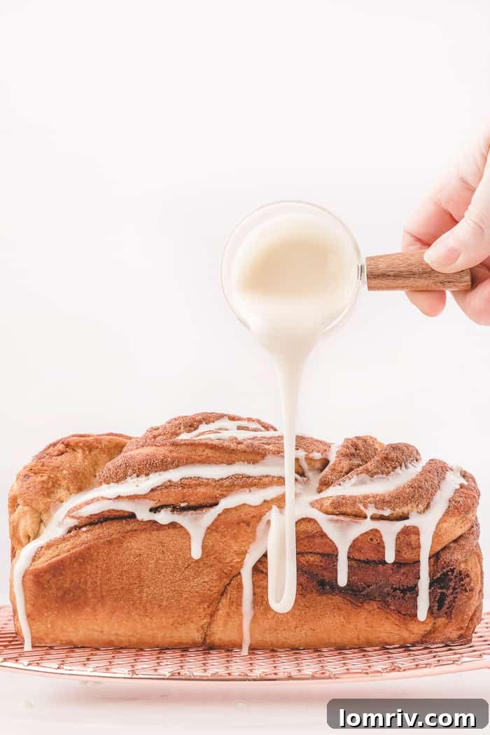 Cinnamon Swirl Bread with a delicate icing being drizzled all over it.