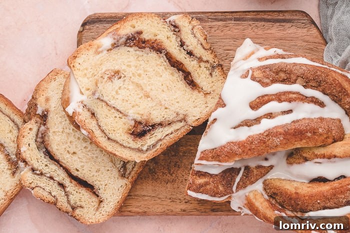 Cinnamon Swirl Bread is shown sliced on a cutting board, ready for serving.
