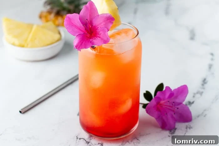 Pineapple Orange Rum Punch in a tall glass with ice and fruit garnishes
