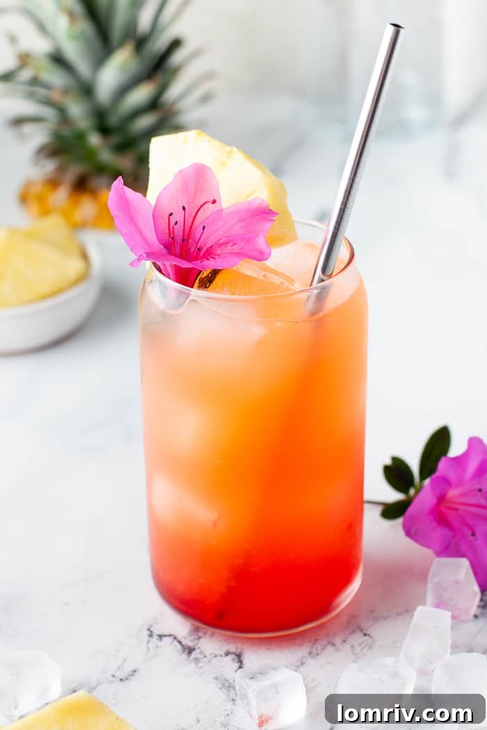 Pineapple Orange Rum Punch in a glass, garnished with fresh fruit, on a wooden surface