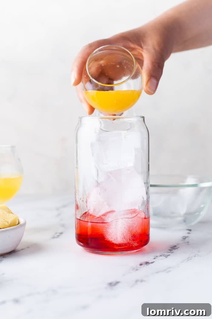 White rum being poured into the glass, creating a layered effect over grenadine