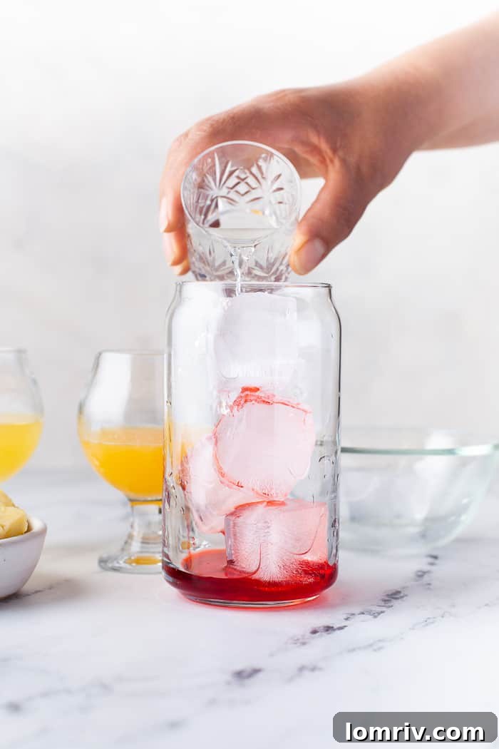 A bar spoon mixing the ingredients of the Pineapple Orange Rum Punch in a glass