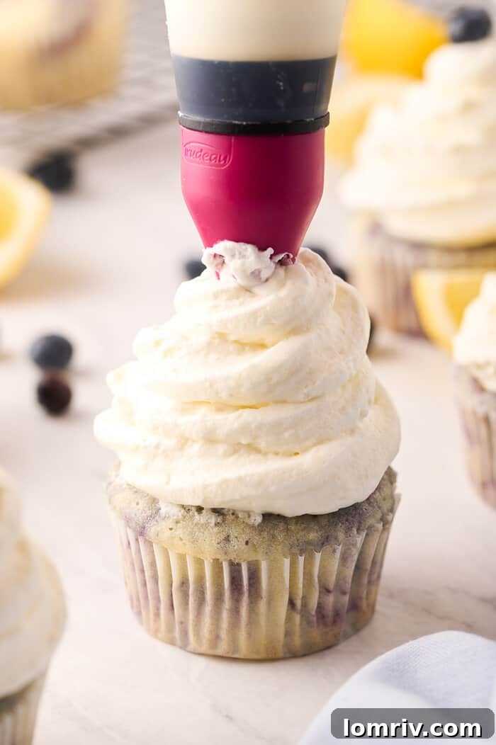 Lemon Blueberry Cupcakes being frosted with cream cheese frosting