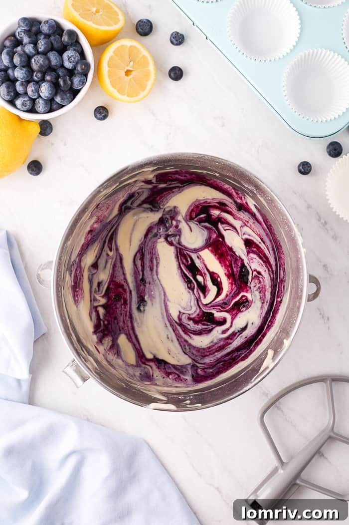 Blueberry compote being swirled into cupcake batter
