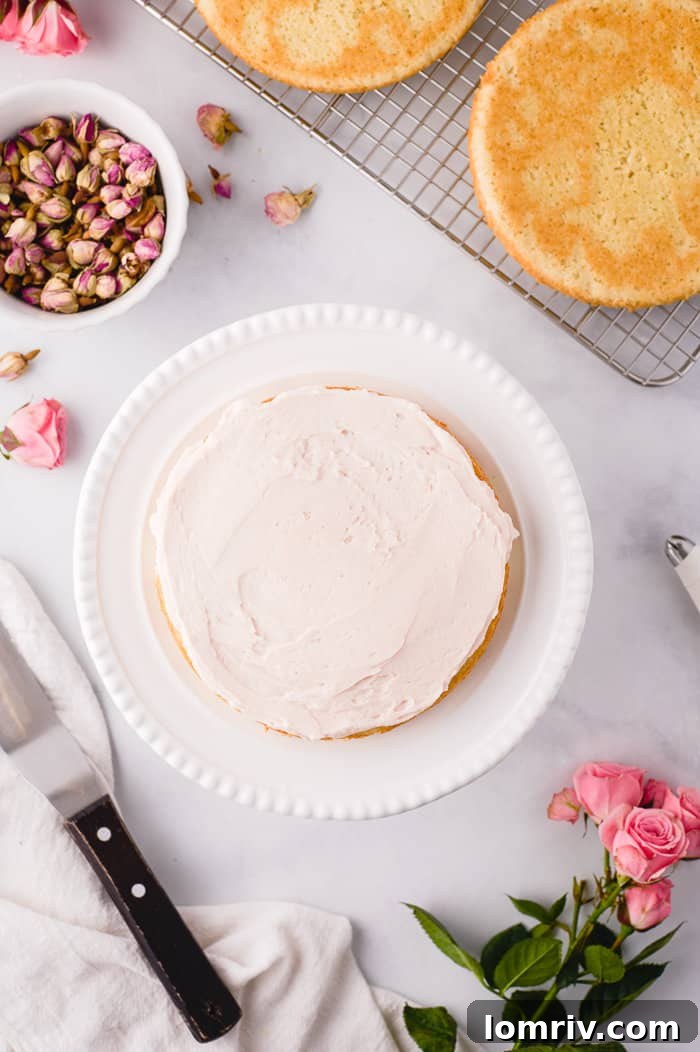 First cake layer being frosted with rose buttercream.