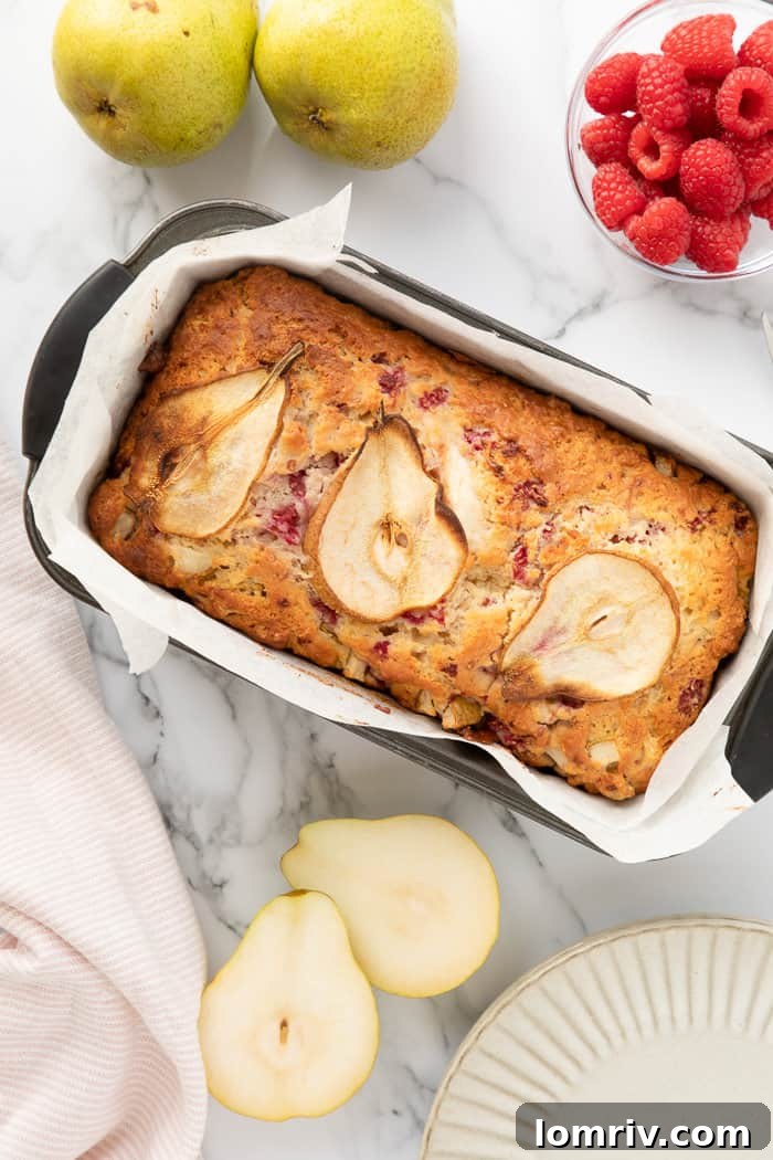 Lush Pear and Raspberry Bread with a subtle marble background, adorned with fresh pear slices and vibrant raspberries.