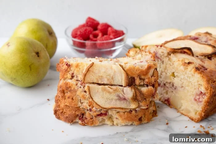 A beautiful cross-section of Pear and Raspberry Bread, showing the fruit distribution, on a marble background.