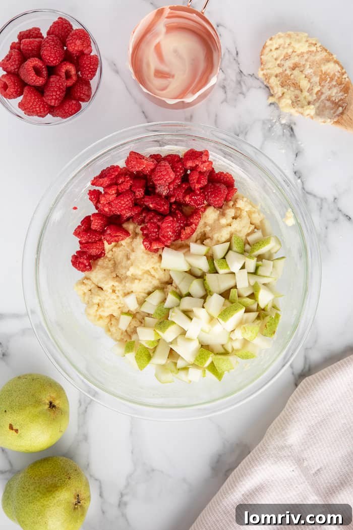 Pear and Raspberry Bread batter scooped into a prepared loaf pan, ready for baking.