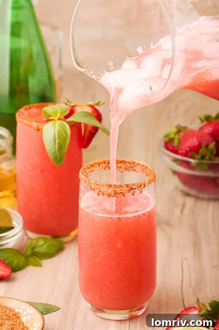 A finished Strawberry Paloma cocktail in a rimmed glass, garnished with basil