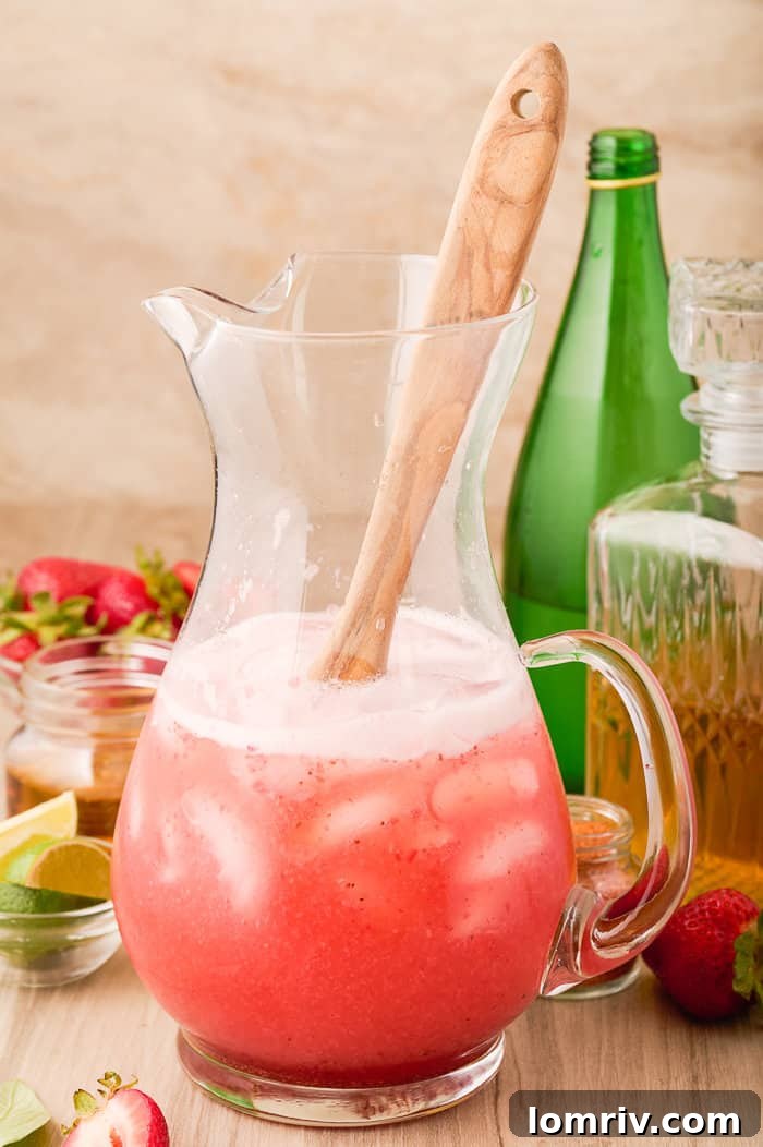 Adding ice and sparkling water to the pitcher of Strawberry Paloma mix