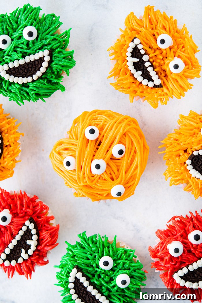A finished monster cupcake with vibrant green fur, two candy eyes, an Oreo mouth, and white frosting teeth.