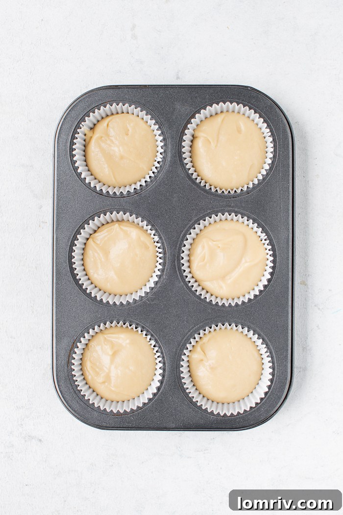 Cupcake batter scooped into liners in a baking tray, ready for the oven.