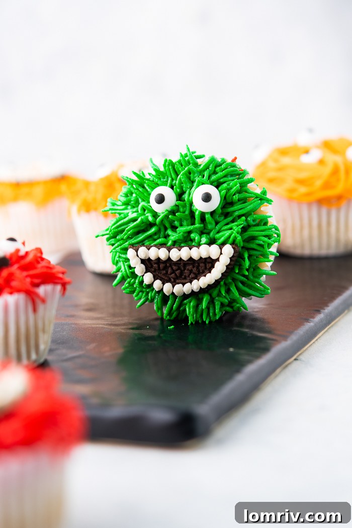 A cupcake being decorated with green frosting using a grass icing tip to create a furry texture.