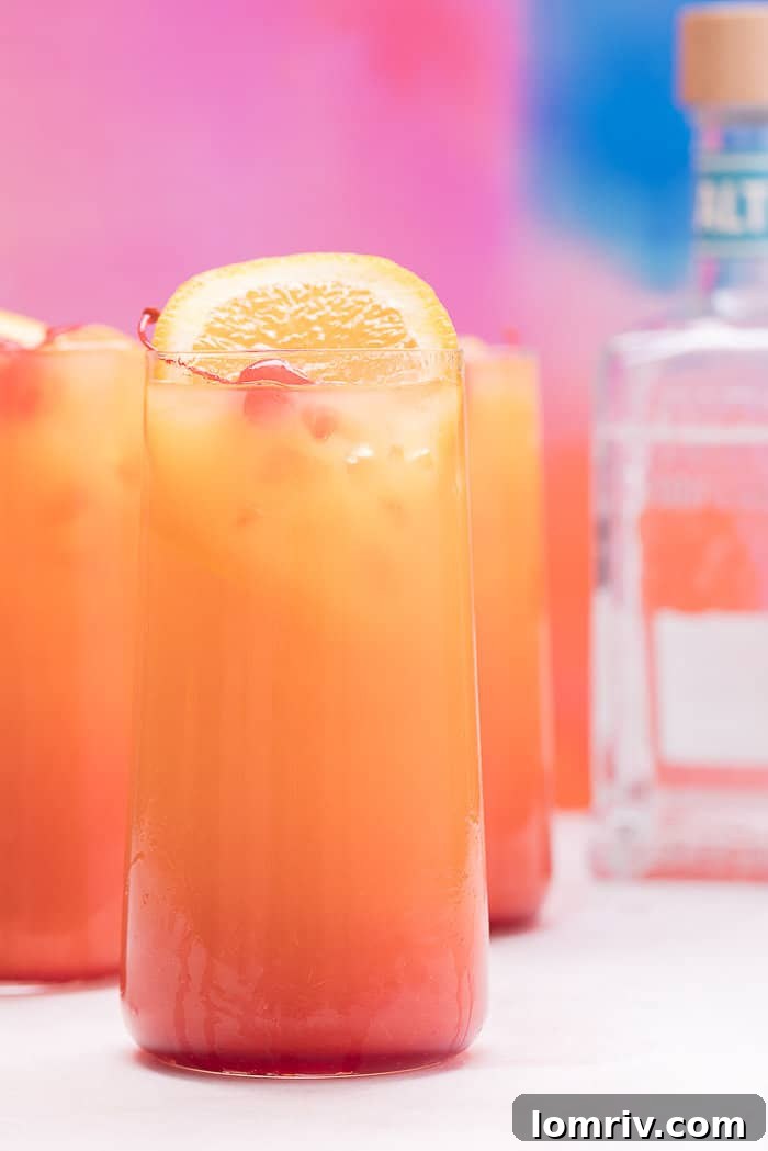 Three tall glasses of Tequila Sunrise, expertly layered and garnished, ready for a gathering.