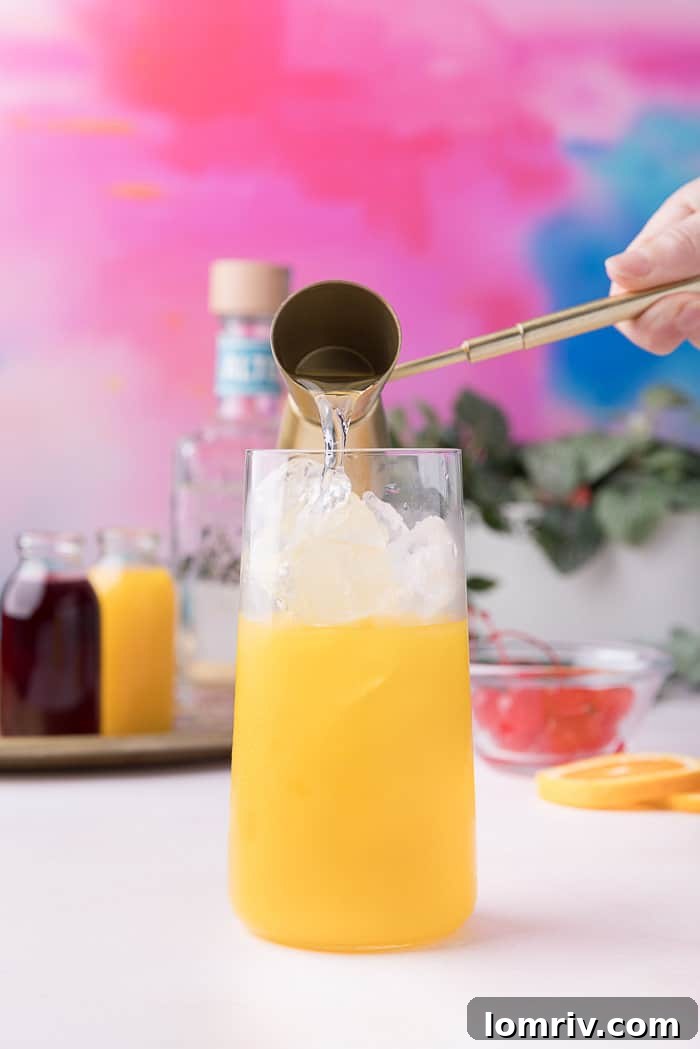 Tequila being poured into the glass, mixing with the orange juice and ice.