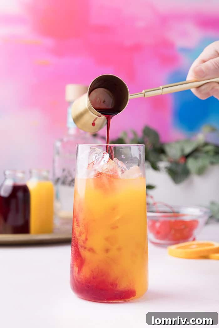 Grenadine being slowly poured into the glass, creating a beautiful red layer at the bottom.