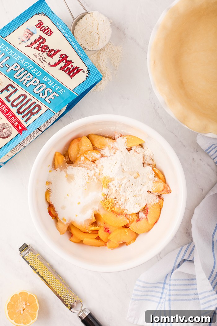Juicy peach filling being spooned into a raw pie crust