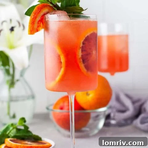 Blood orange cocktail in a glass with blood orange slices.