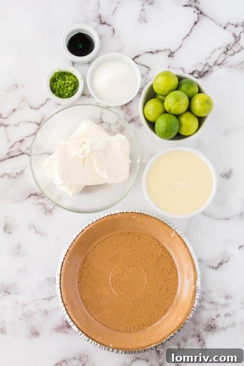 All the essential No Bake Key Lime Pie ingredients laid out on a kitchen counter, including key limes, cream cheese, condensed milk, and a graham cracker crust.